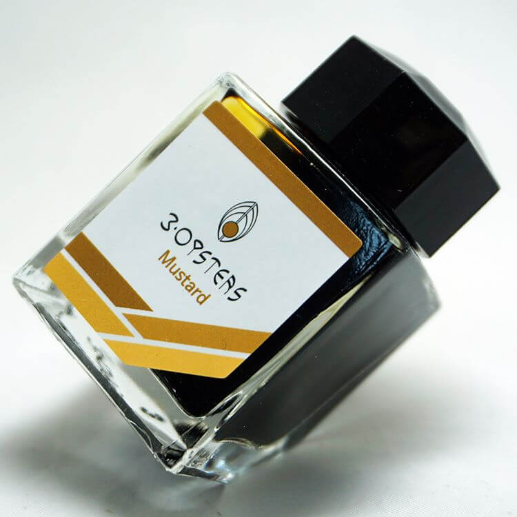 3 Oysters Mustard from the Delicious collection is a medium brown-yellow fountain pen ink with medium shading. It dries in 30 seconds in a medium nib on Rhodia and has a dry flow. The glass bottle has a cut out corner to lean the bottle for a decorative display. 3 Oysters ink is made in Korea. Pantone color: 1245C