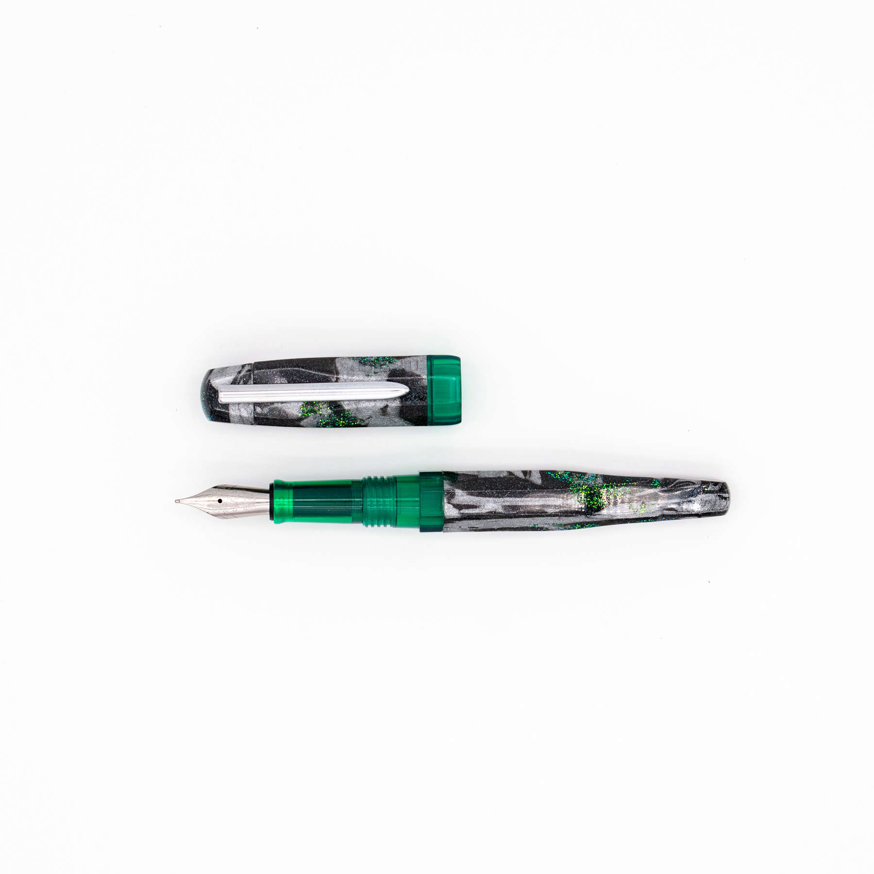 A fountain pen and its cap shown on a plain white background. The pen has a translucent green grip and cap band with a black and silver marbled body with green shimmer accents, with a silver clip and a silver nib.
