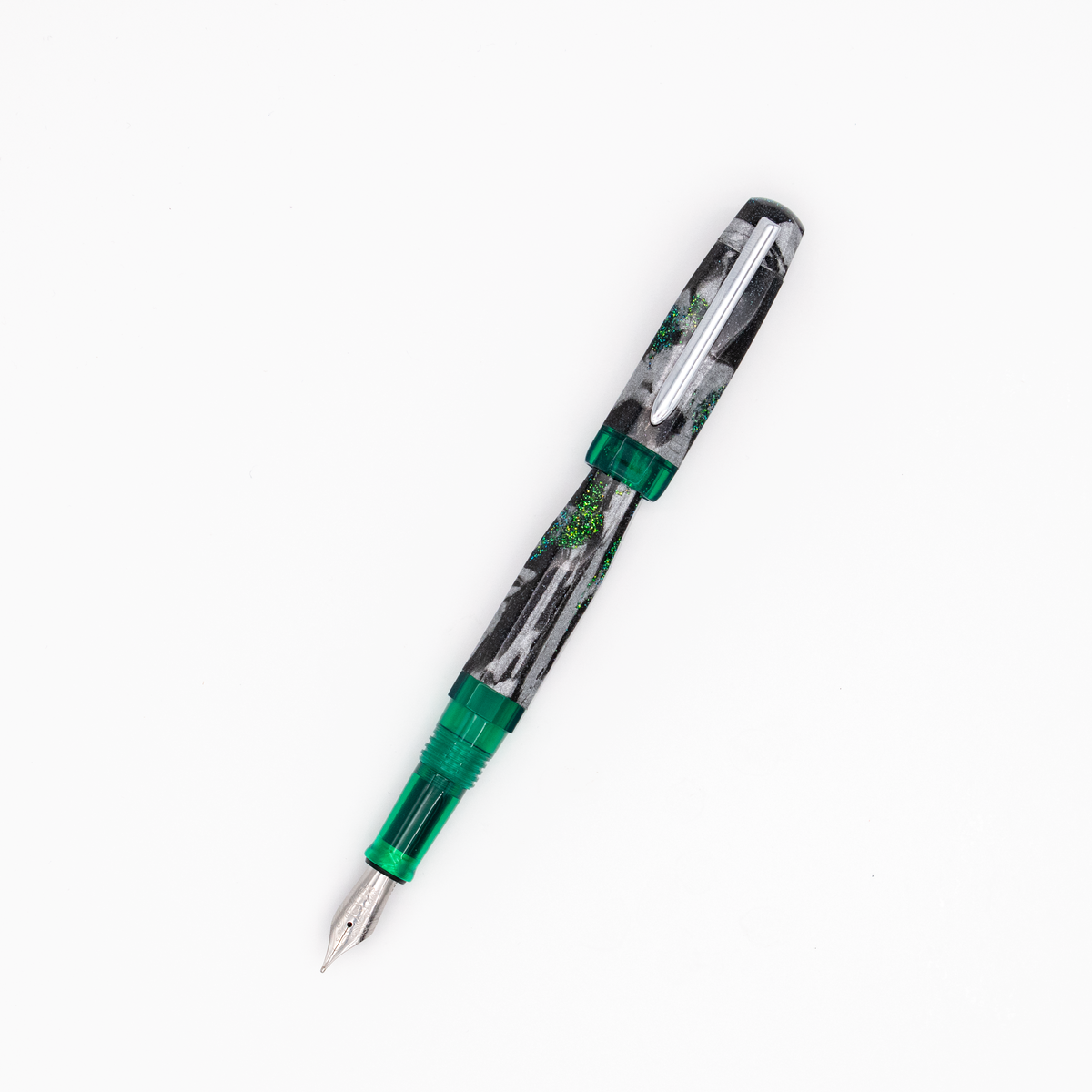 A fountain pen with a shimmer black, silver, and green marble patterned barrel with translucent green accents and a silver clip, shown diagonally on a plain white background.