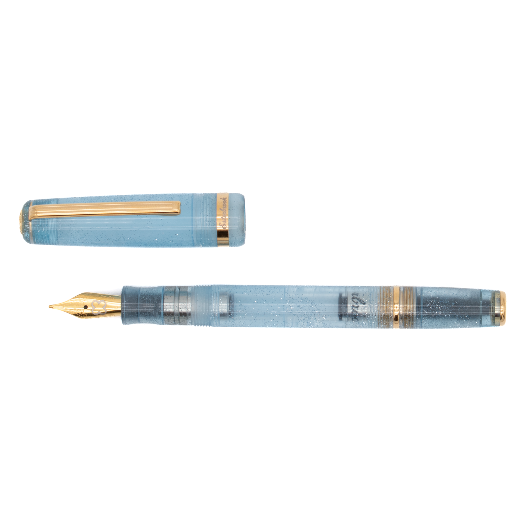 A light blue transparent fountain pen with silver glitter accents along the barrel, gold trim, a gold nib. The cap is off and placed parallel to the pen and is shown diagonally on a plain white background.