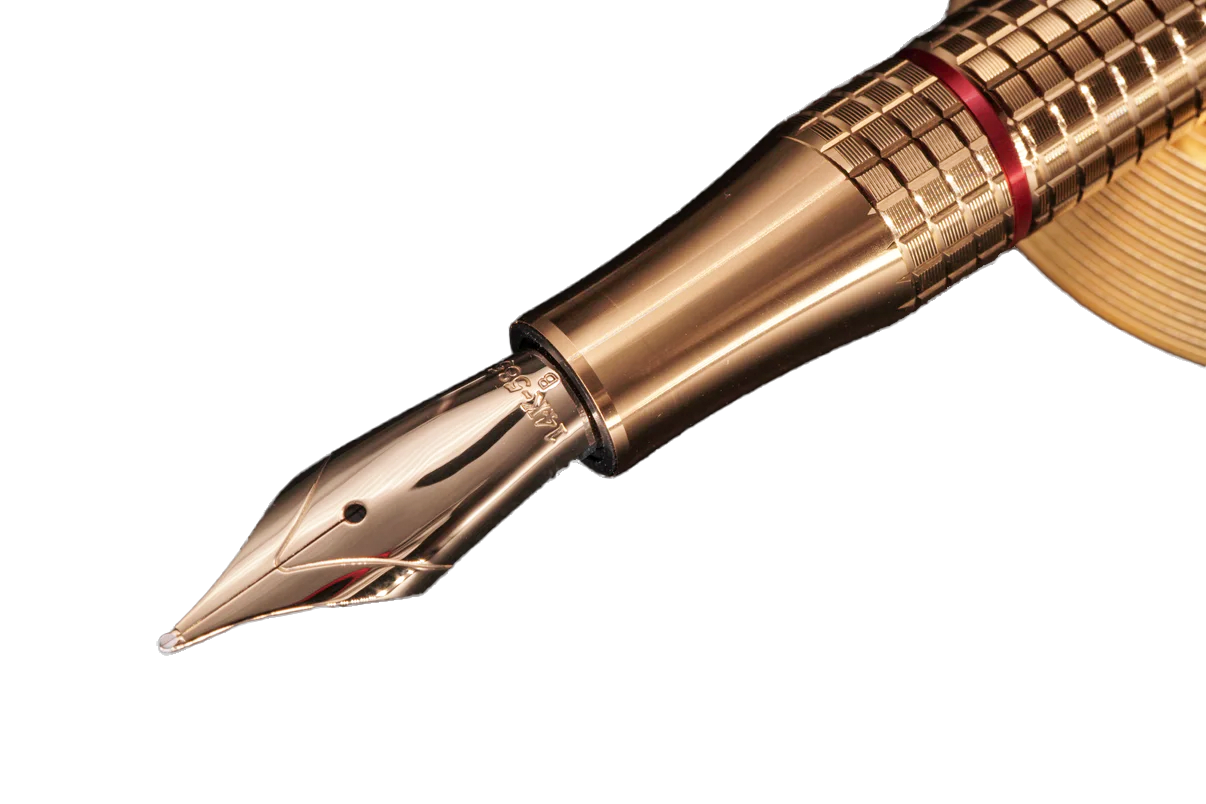 Close-up of a gold fountain pen nib and upper barrel in polished gold metal, featuring a textured grip section with a thin red accent ring, on a solid white background.