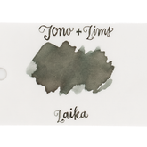 An ink swatch in a gray-green on white paper, with the text 'Tono+Lims' at the top and 'Laika' at the bottom in matching script on a plain white background.