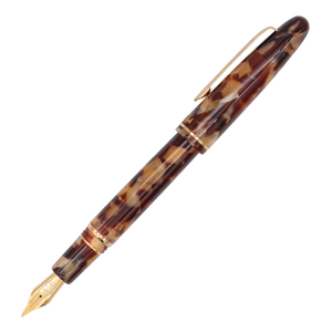 Tortoise shell and gold trim fountain pen with the cap posted on its barrel diagonally on a plain white background.